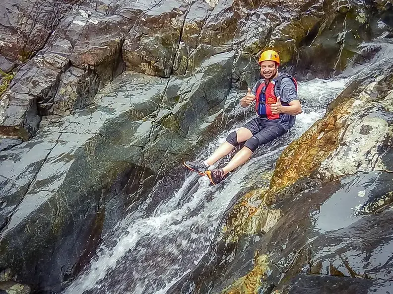 Guest sliding down a natural rock waterslide on a guided El Yunque tour